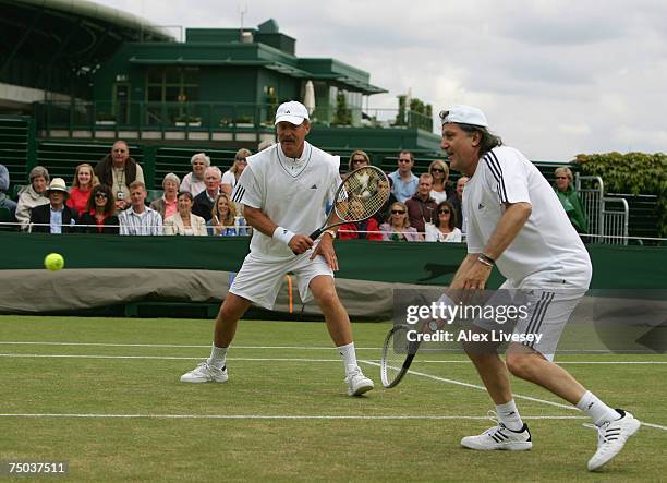 Ilie Nastase of Romania plays a forehand as partner Stan Smith of USA looks on during the Senior Gentleman's Invitational Doubles match against...