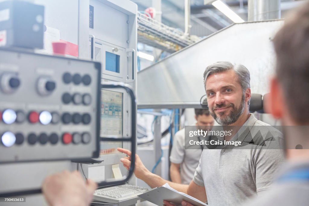 Portrait smiling male manager at machinery control panel in factory