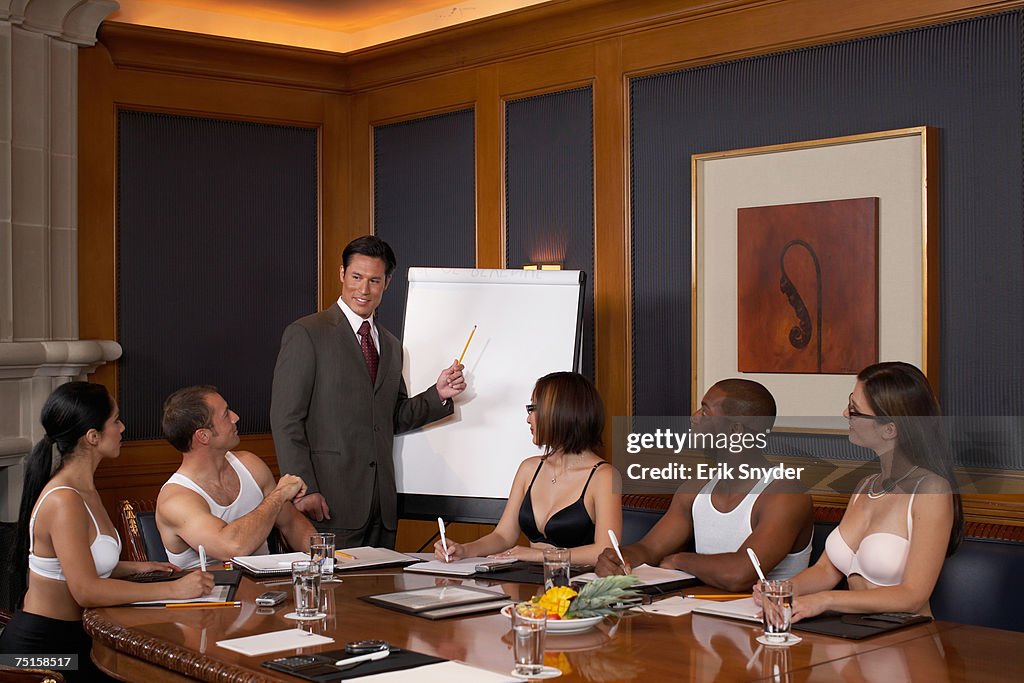 Business man giving presentation while colleagues wearing underwear are listening