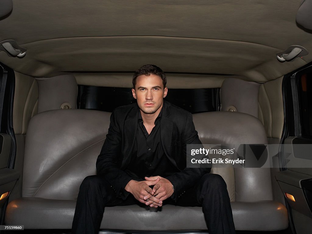 Portrait of young man sitting in limousine, front view