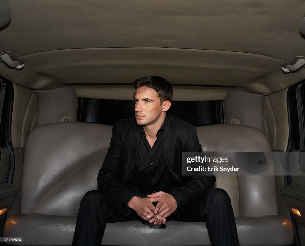 Young man sitting in limousine, looking aside