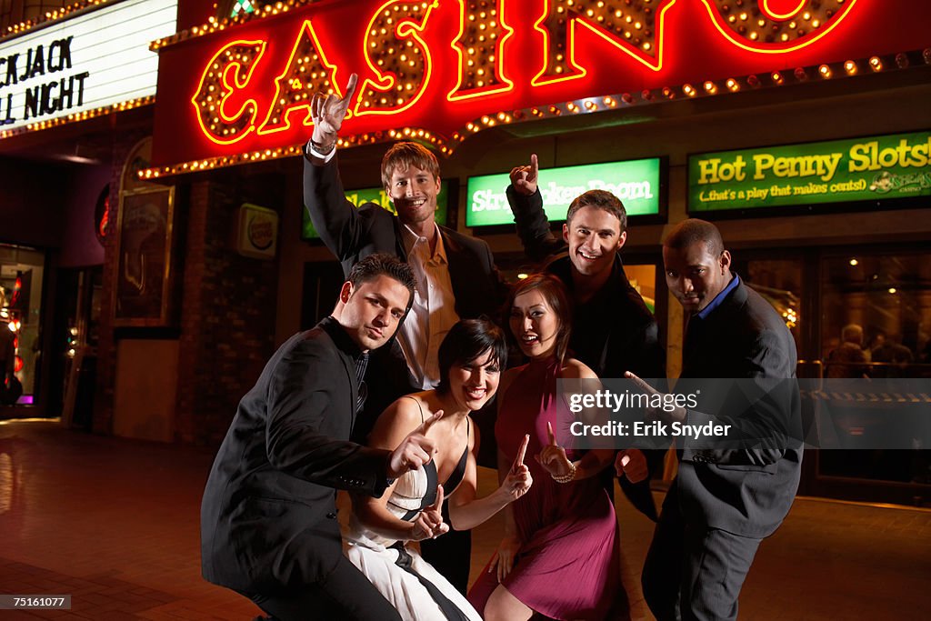 Group portrait of people posing in front of casino at night, laughing