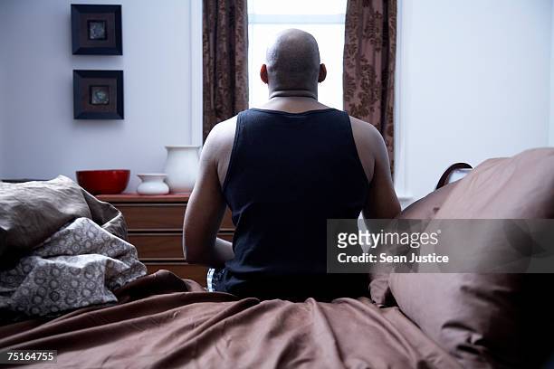 mature man sitting on bed, rear view - waking up in bed stock pictures, royalty-free photos & images