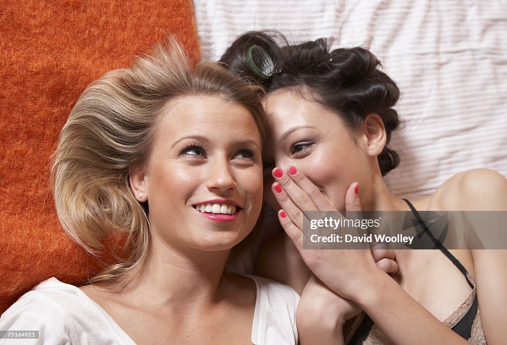 Young woman and teenage girl (16-17) lying on bed, smiling, overhead view