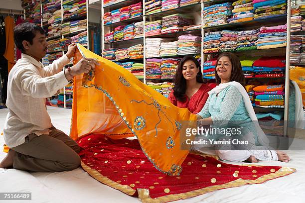 women selecting sari in sari shop - woman in red sari stock-fotos und bilder