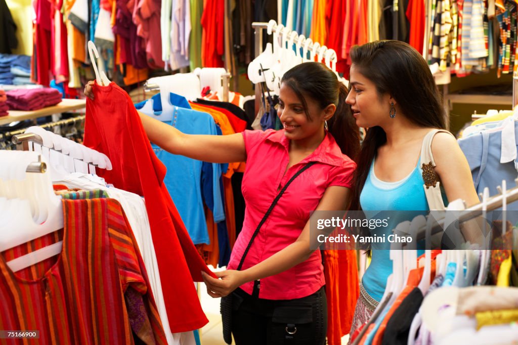 Salesgirl showing dress to woman in supermarket