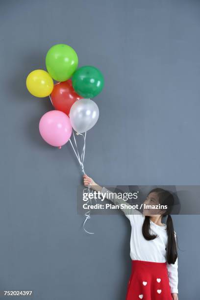 a girl holding colorful balloons - child balloon studio photos et images de collection