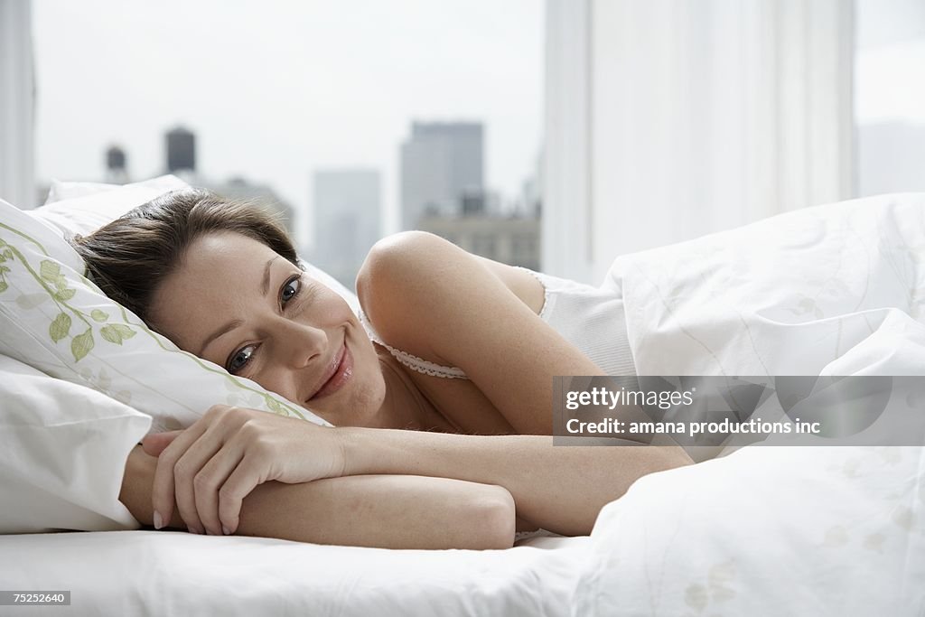 Mid adult woman in bed (portrait)