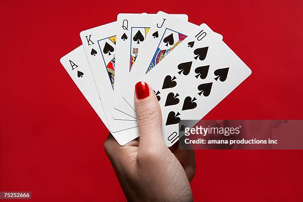 woman's hand holding 'royal flush' hand of cards - reine de pique photos et images de collection