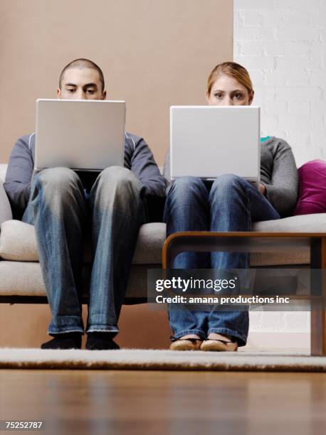 young couple using laptops on sofa, low angle view - coffee table low angle stock pictures, royalty-free photos & images