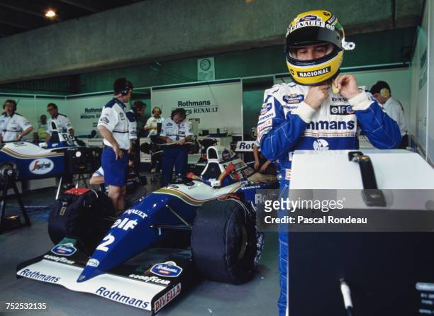 Ayrton Senna pulls on his helmet before he drives the Rothmans Williams Renault Williams FW16 Renault V10 during practice for the Brazilian Grand...