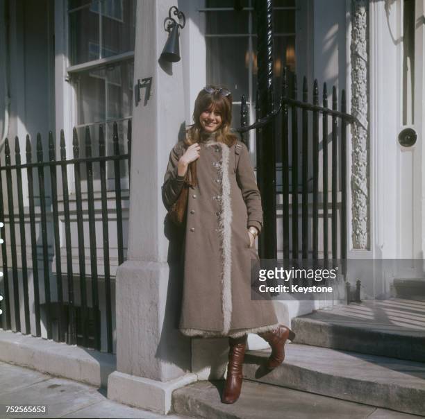 English-Australian singer, Olivia Newton-John, wearing a three-quarter length coat and boots, London, circa 1970.