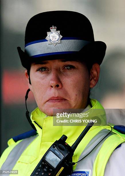 London, UNITED KINGDOM: An unidentified policewoman stands outside Kings Cross Station as people lay flowers at a memorial to mark the second...