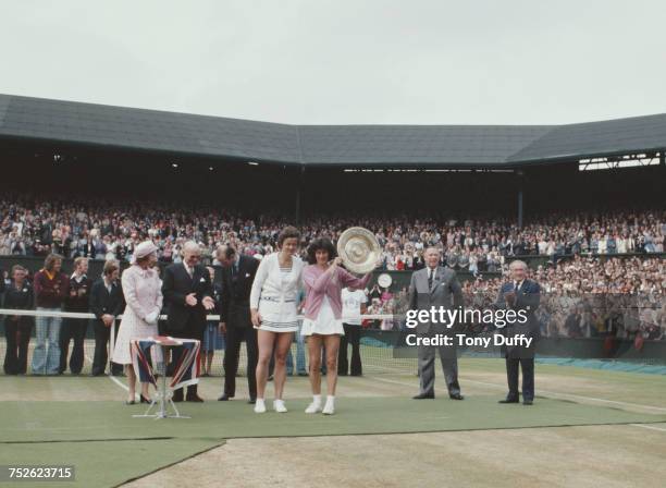 Queen Elizabeth II looks on as Virginia Wade of Great Britain holds aloft the Venus Rosewater Dish after defeating Betty Stove in their Women's...