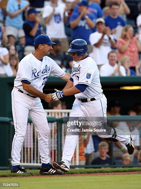 Billy Butler of the Kansas City Royals is congratulated by Brian Poldberg as he rounds third after hitting a home run during the game against the...