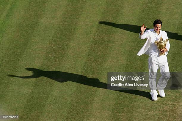 Roger Federer of Switzerland parades the trophy as he celebrates victory following the Men's Singles final match against Rafael Nadal of Spain during...