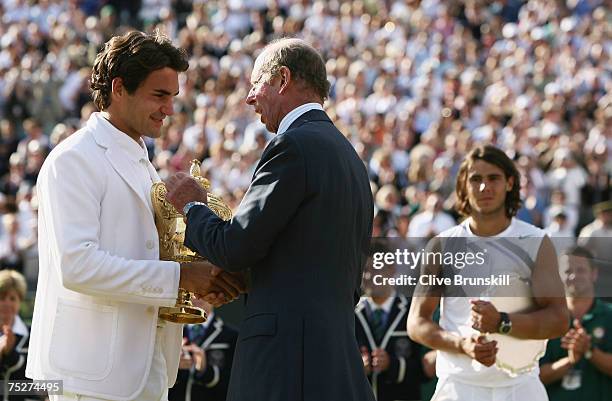 Roger Federer of Switzerland receives the trophy from The Duke of Kent as Rafael Nadal of Spain looks on following the Men's Singles final match...