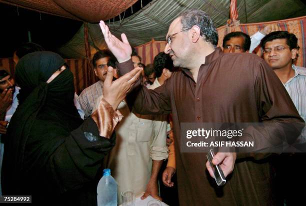 Pakistani Information Minister Mohammad Ali Durrani listens to a female relative of a religious student who is inside the Red Mosque after holding...