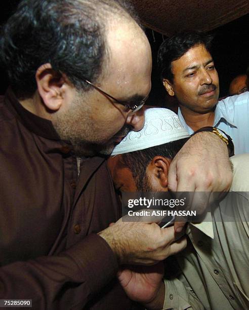 Pakistani Information Minister Mohammad Ali Durrani hugs with a relative of a religious student who is inside the Red Mosque after holding talks with...