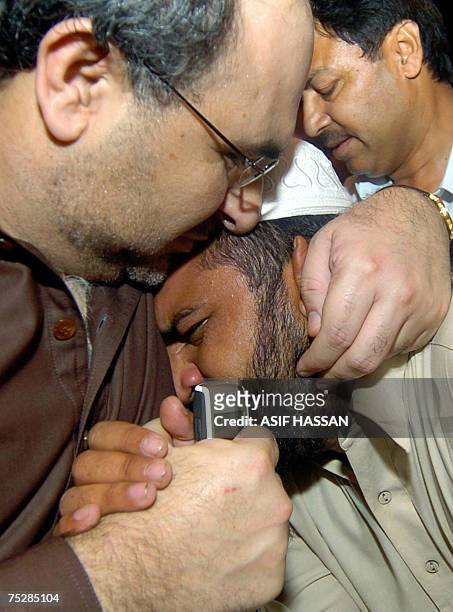 Pakistani Information Minister Mohammad Ali Durrani hugs a relative of religious student who is inside the Red Mosque after holding talks with...