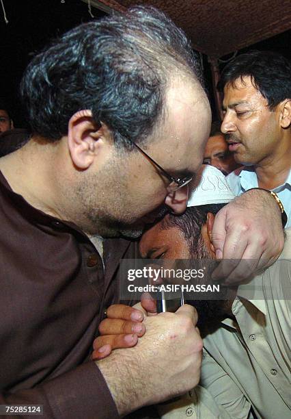 Pakistani Information Minister Mohammad Ali Durrani hugs with a relative of a religious student who is inside the Red Mosque after holding talks with...