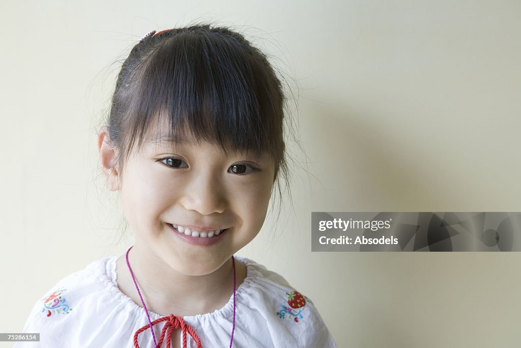 A smiling girl standing against wall