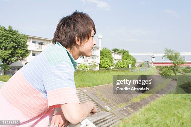 a young man sitting in a river bank - 河川敷 ストックフォトと画像