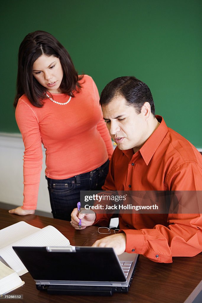 Teacher explaining student, using laptop