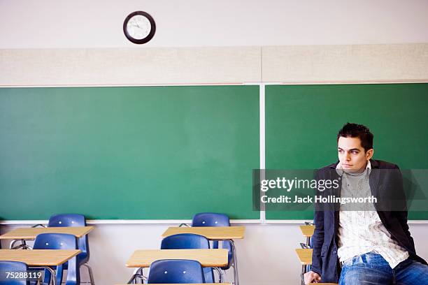 student sitting on desk in classroom - classroom-front-view stock-fotos und bilder