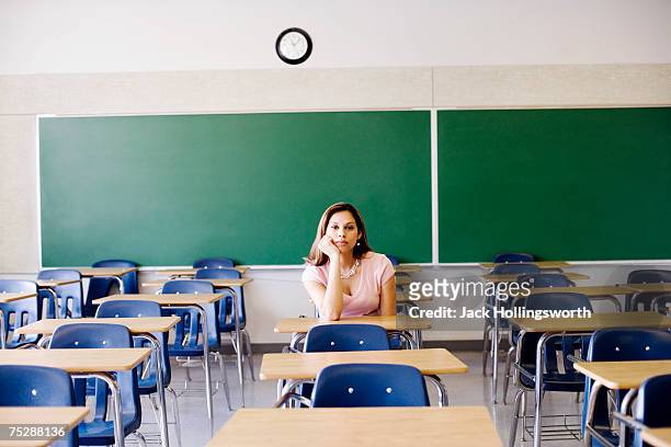 student sitting in empty classroom - clock person desk stockfoto's en -beelden