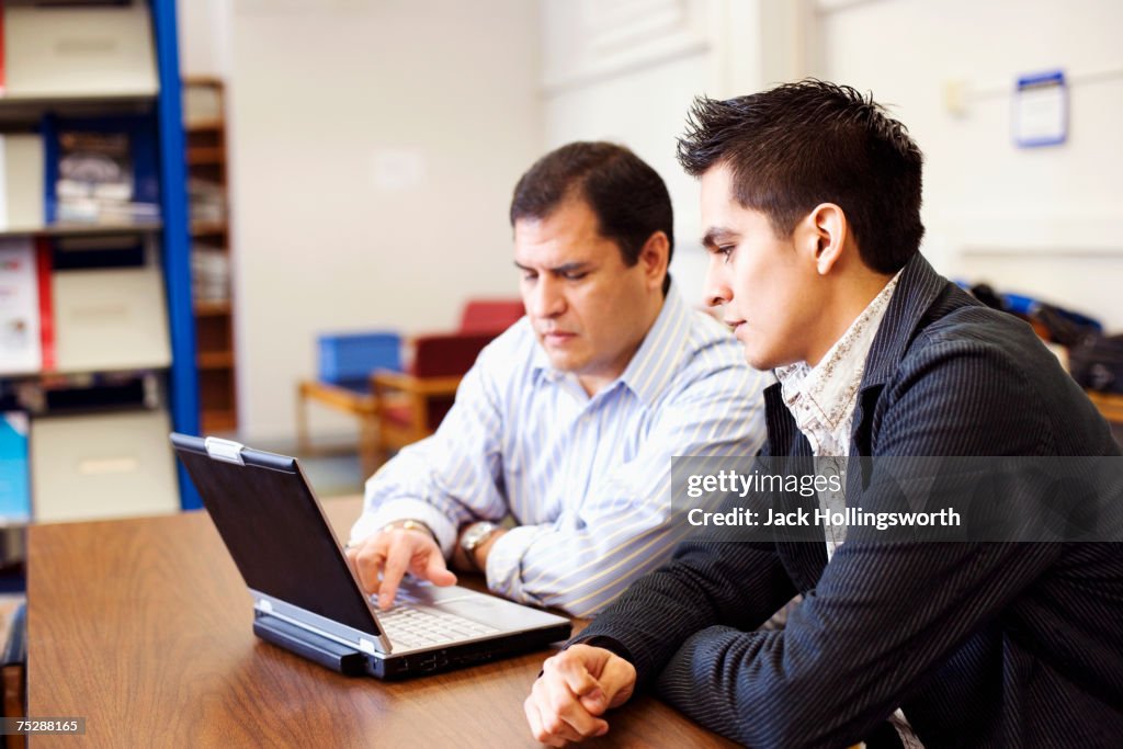 Teaching  student in library, using laptop