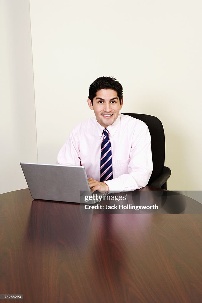 Businessman smiling, using laptop