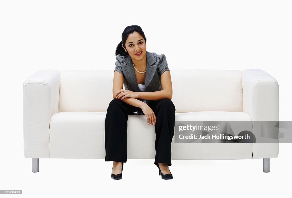 Young woman sitting on couch, smiling, portrait