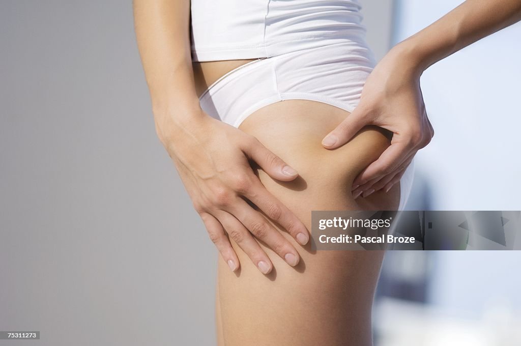 Woman pinching thigh, close-up