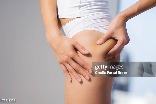 woman pinching thigh, close-up - cellulite stock pictures, royalty-free photos & images