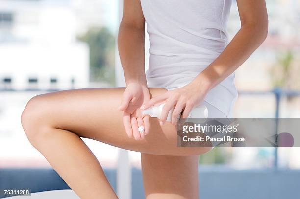 young woman using moisturizer - thigh human leg imagens e fotografias de stock
