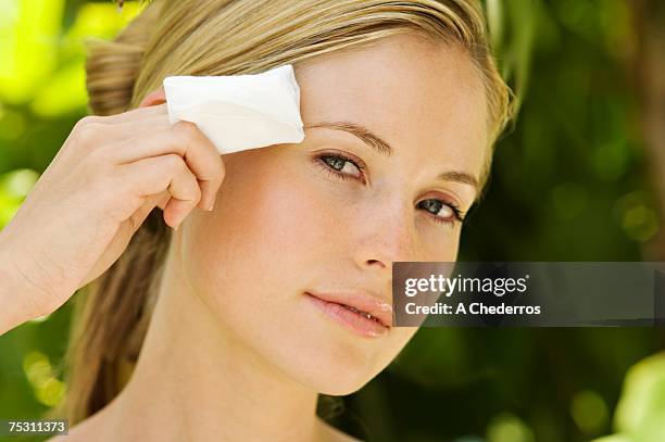 portrait of a young woman using a cleansing cotton on her face, outdoors - wet wipe stock pictures, royalty-free photos & images