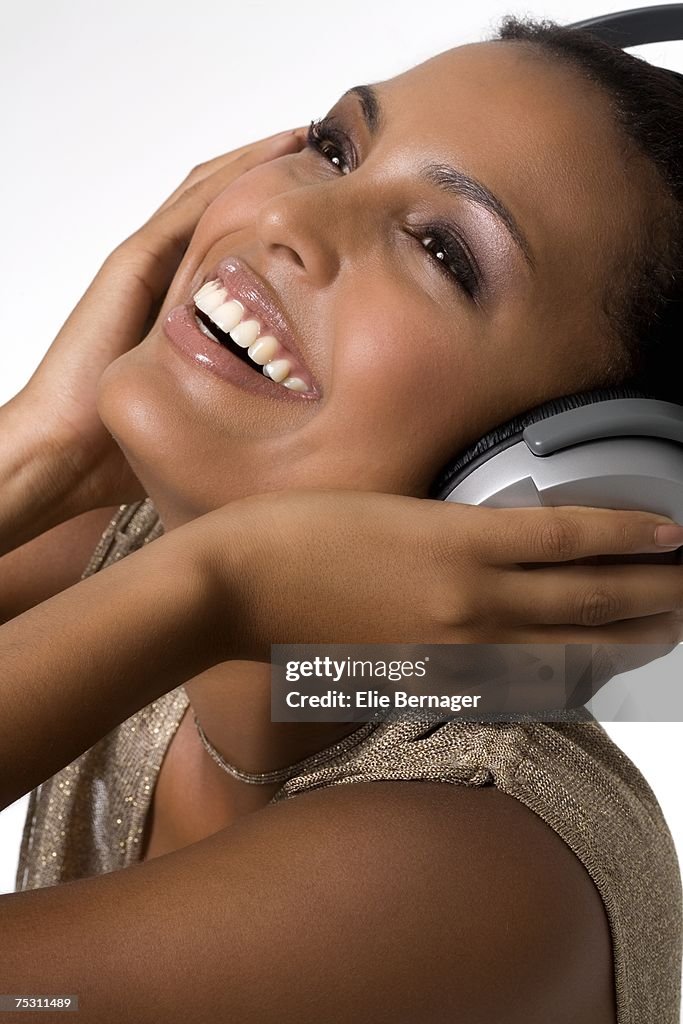 Portrait of a young smiling woman, listening to music with headphones