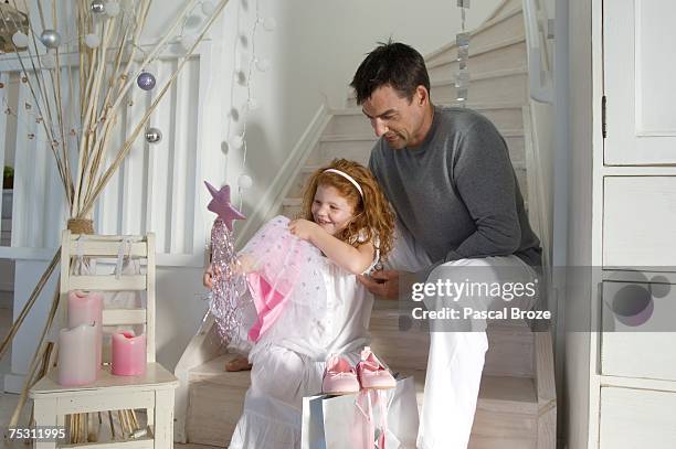 father and daughter opening christmas presents, girl holding a princess costume, indoors - princess party stock pictures, royalty-free photos & images