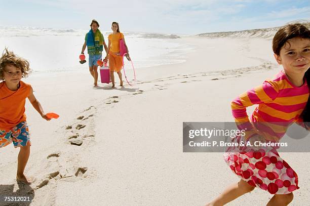 parents et two children walking on the beach, outdoors - couple et vacances stock pictures, royalty-free photos & images