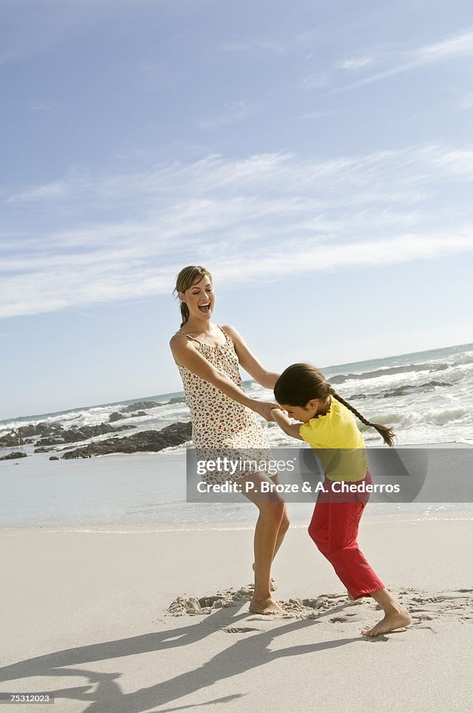Mother and daughter playing on the beach, outdoors