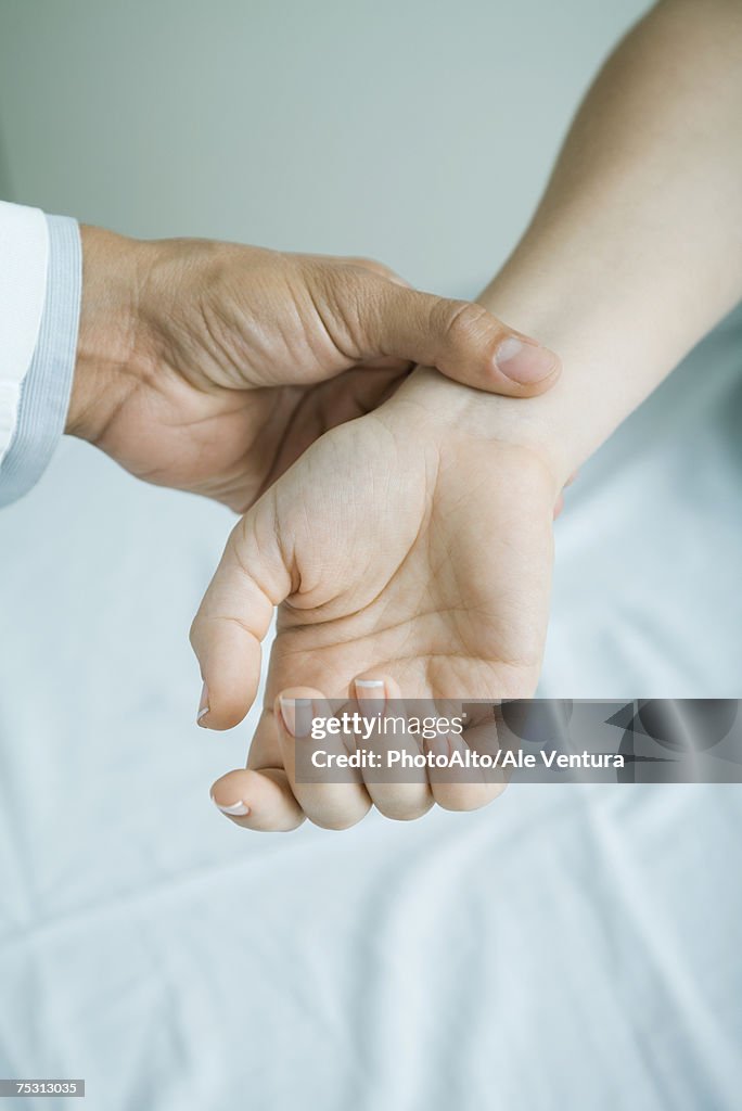 Doctor taking woman's pulse, close-up