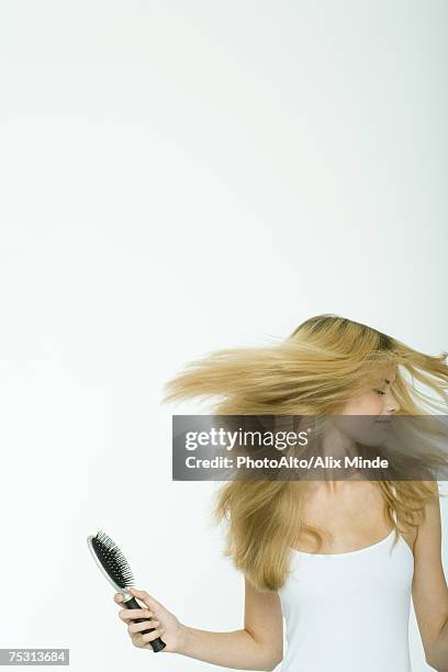 teenage girl holding brush and swinging hair - hair toss stock pictures, royalty-free photos & images