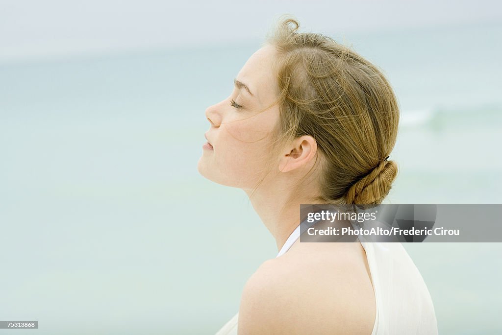 Young woman, head and shoulders, side view, sea in background