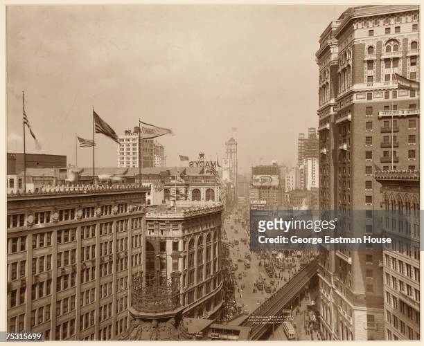 View along Broadway as it passes Herald Square, New York, New York, 1912. The elevated train track is above Avenue of the Americas. Visble structures...