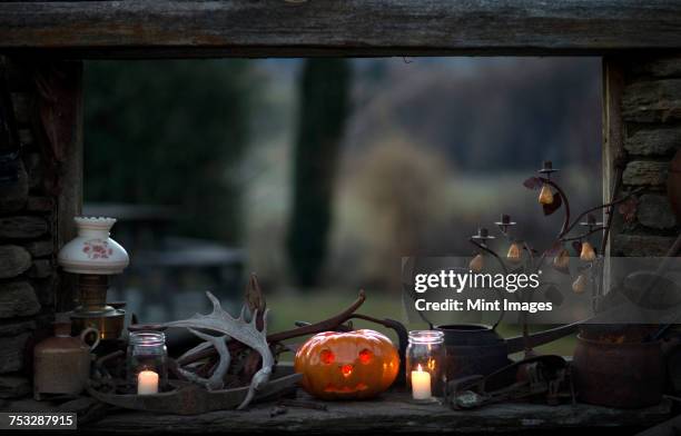 windowsill in a rustic cabin with pumpkin, candles, candle holder, lamp and antlers. - ledge stock pictures, royalty-free photos & images