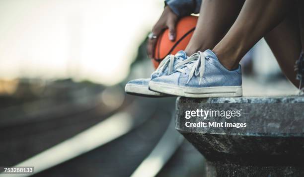 close up of a pair of feet on a railway station platform next to a basketball, with a train behind. - blonde long legs 個照片及圖片檔