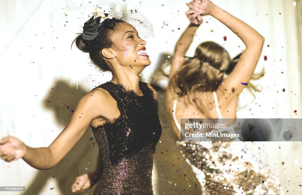 Two young women dancing with confetti falling.