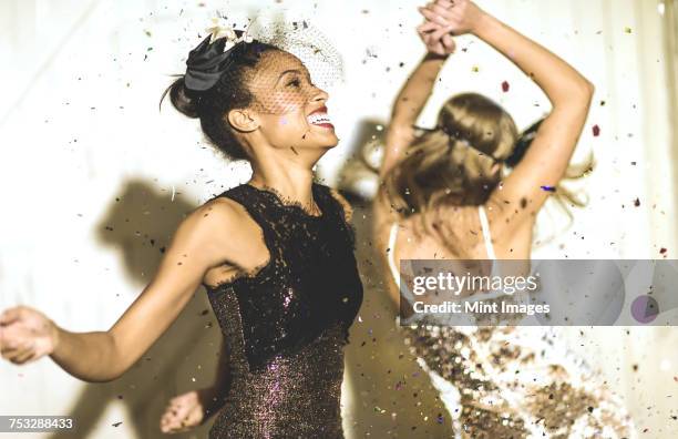 two young women dancing with confetti falling. - black dress party stock pictures, royalty-free photos & images