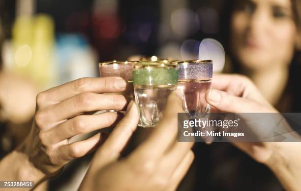 a group at a party holding shot glasses and celebrating. - shot glass stock-fotos und bilder